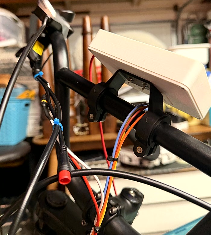 The Waveshare ESP32-S3 touchscreen in its printed enclosure clamped to the handlebars with wiring harness routed down the stem.